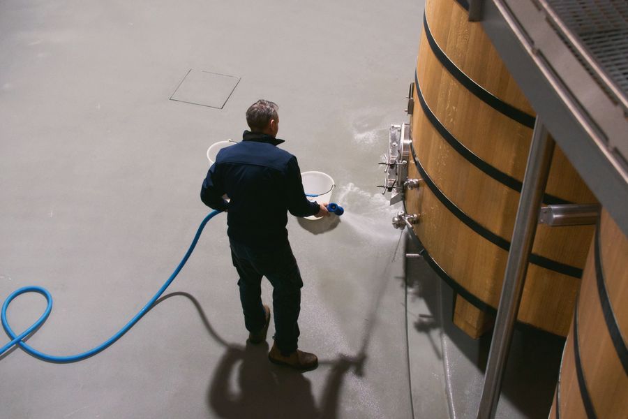 Un vigneron nettoie des fûts de chêne dans un chai à Pauillac